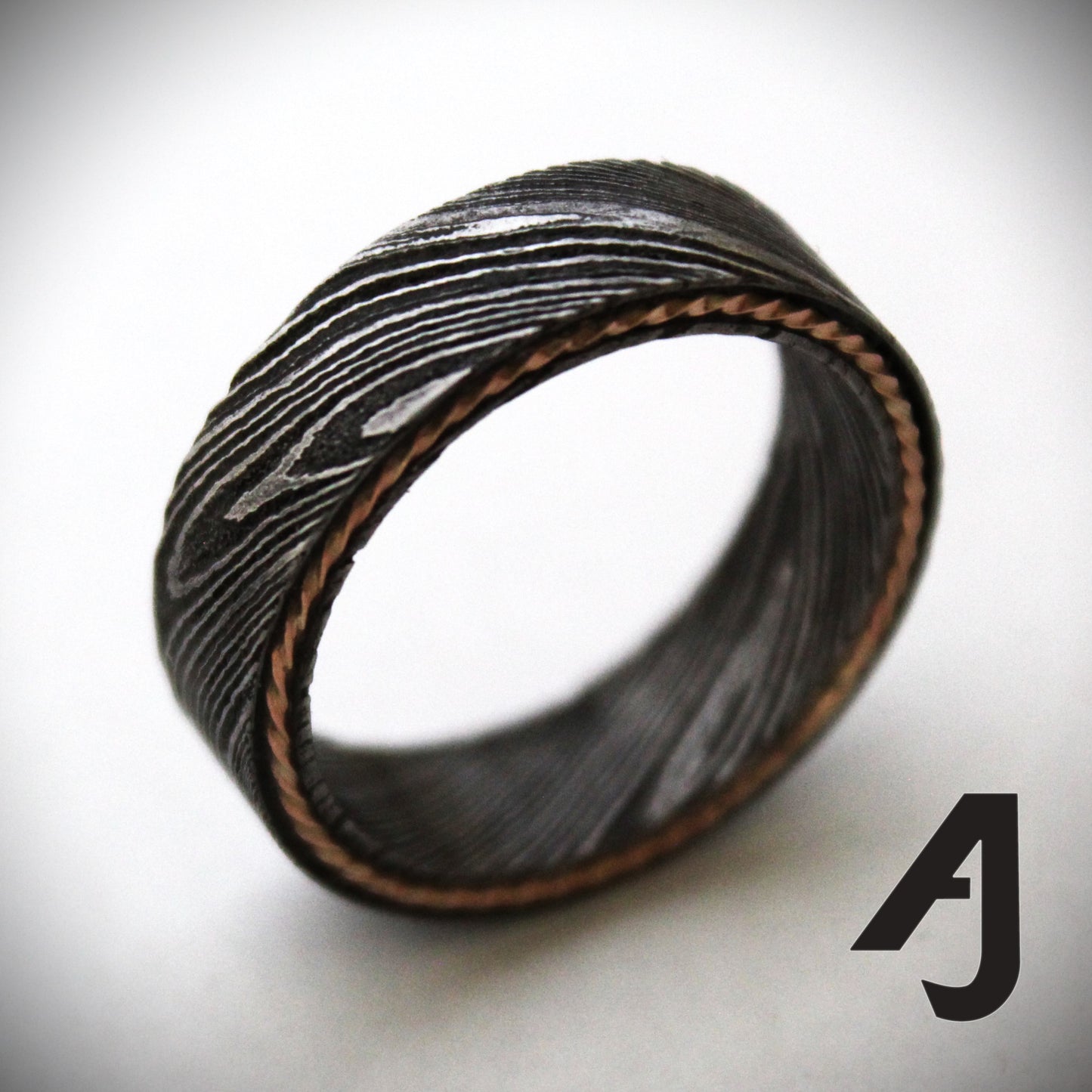 Damascus steel ring with a twisted rose gold inlay, showcasing unique wavy patterns and a blend of rugged durability with elegant warmth