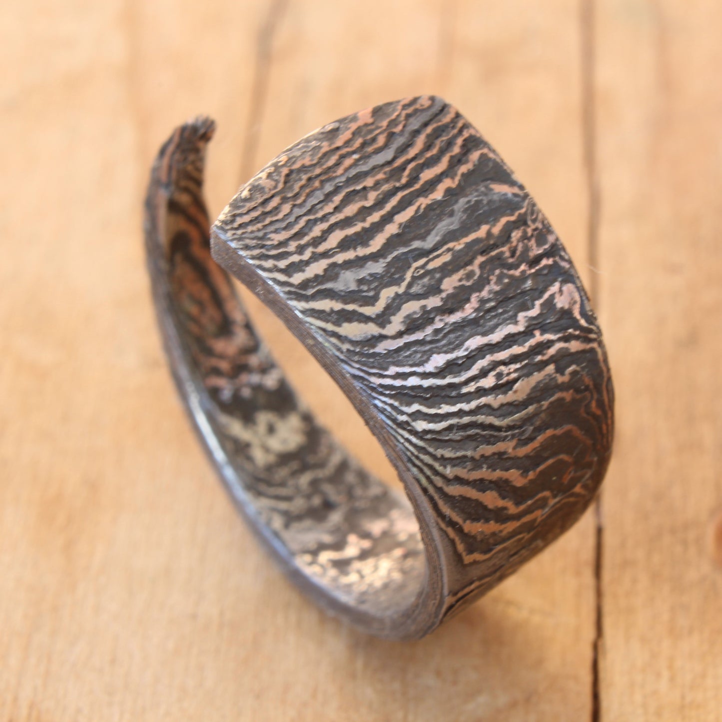 Hand-forged Damascus Steel knife blade ring, polished to reveal unique patterns and intricate lines, showcasing one-of-a-kind artistry and craftsmanship.