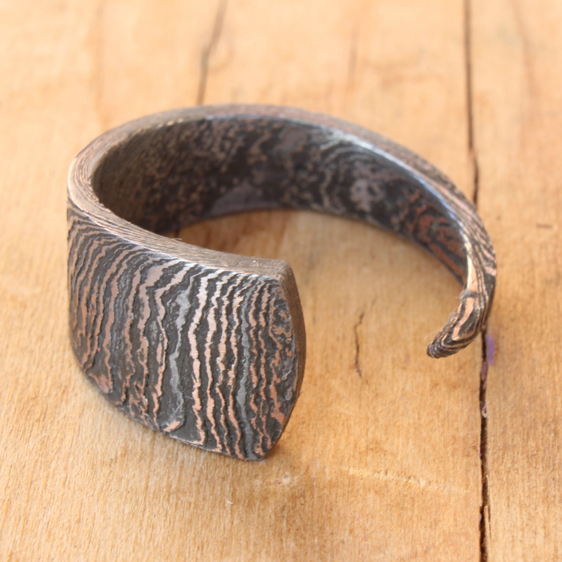 Hand-forged Damascus Steel knife blade ring, polished to reveal unique patterns and intricate lines, showcasing one-of-a-kind artistry and craftsmanship.